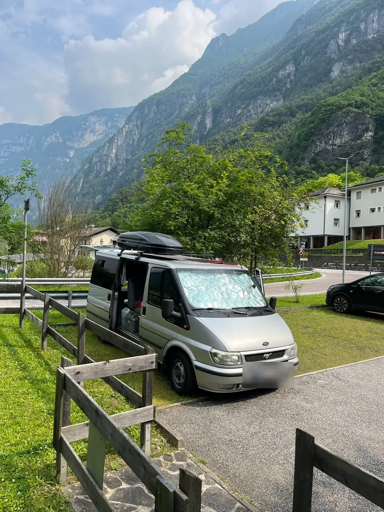 Naše dodávka na parkovišti v Tezze Valsugana pod zalesněnými horami