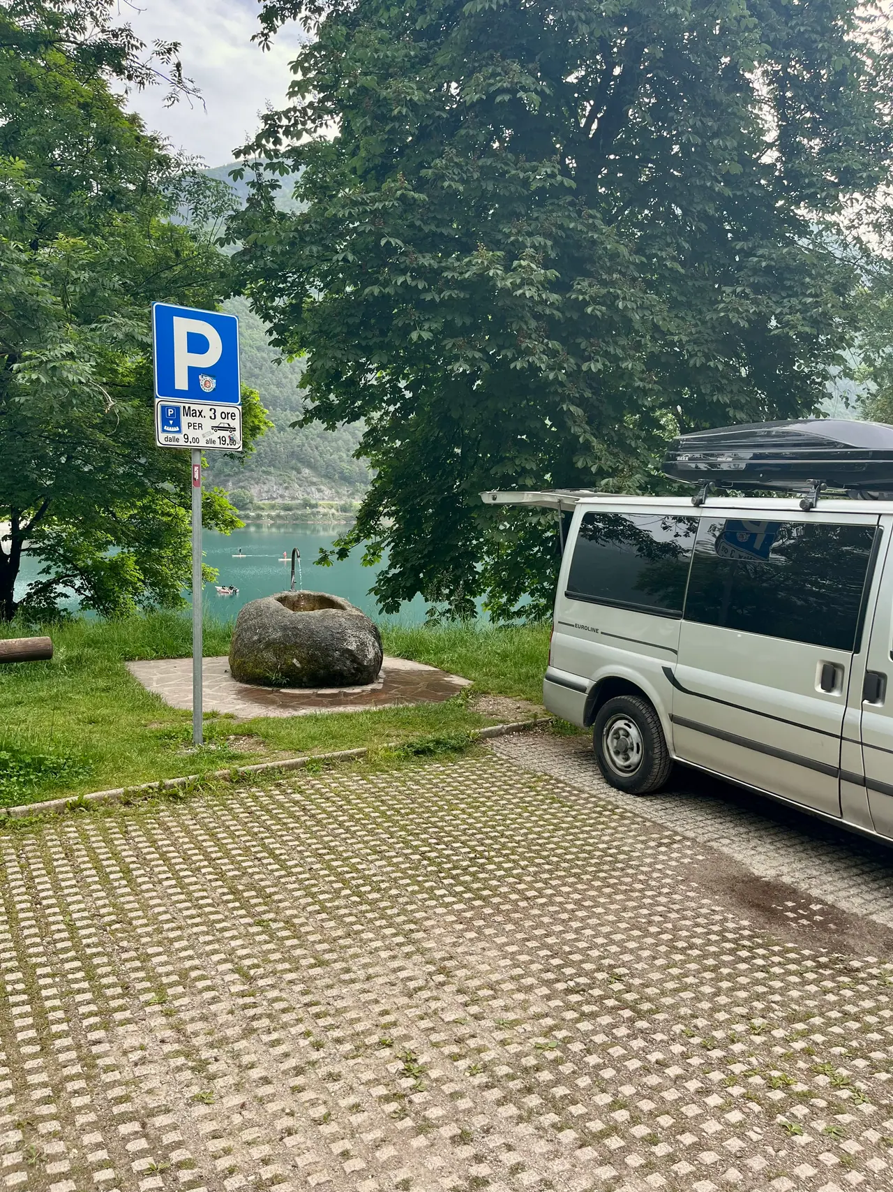 Naše dodávka na parkovišti s dlažbou u Lago di Ledro v Mezzolagu