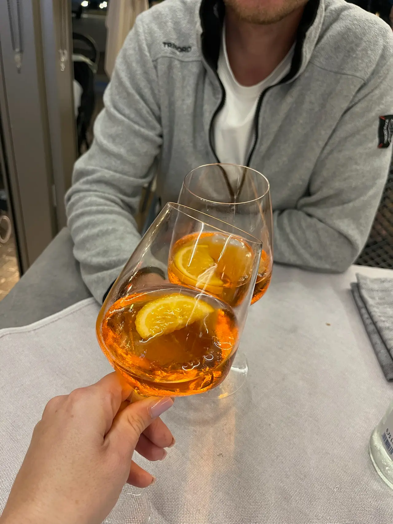 Sklenka Aperol spritz v ruce u večeře v restauraci v Caorle