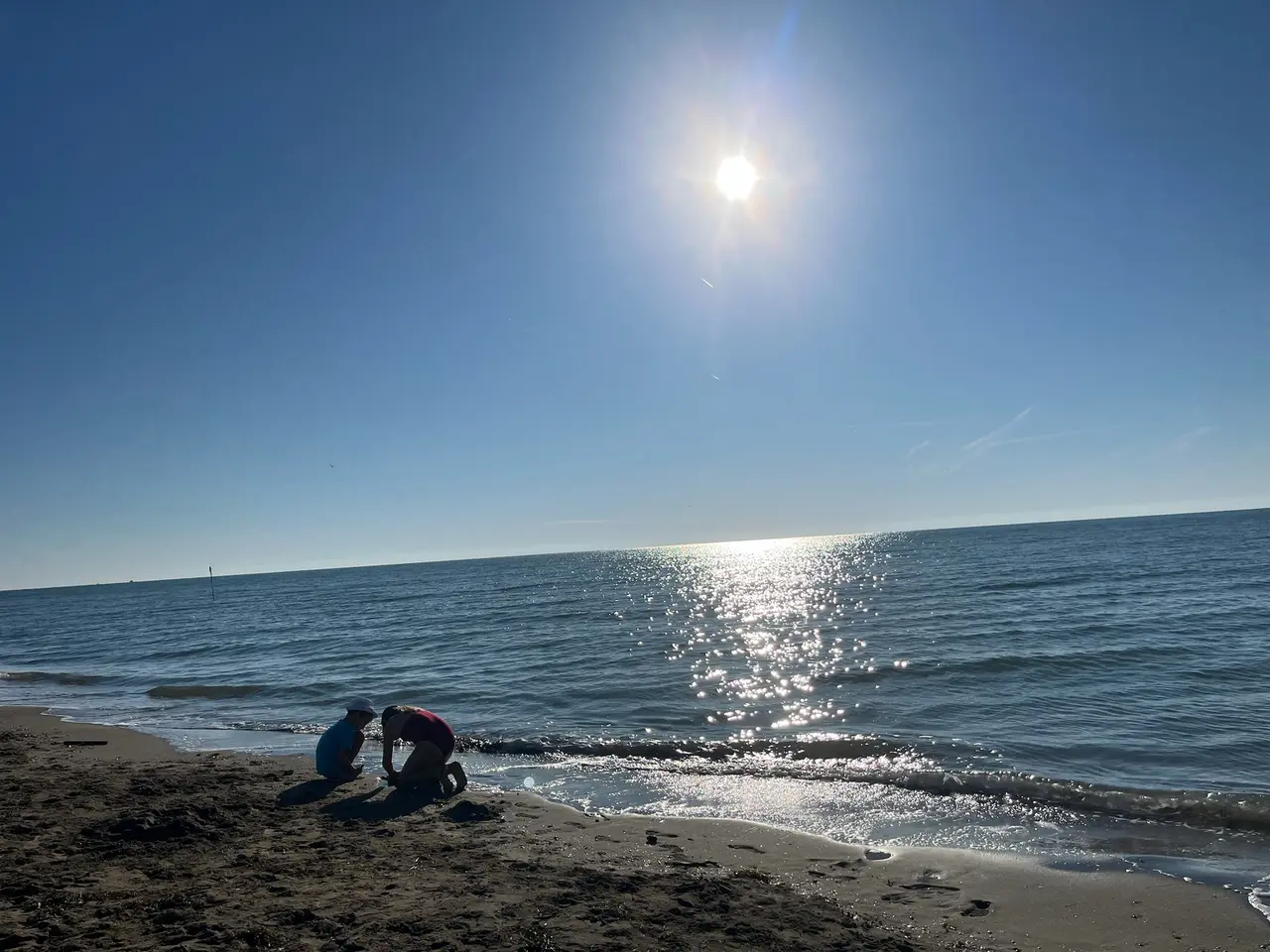 Děti si hrají u vody na pláži v Caorle ráno v protisvětle