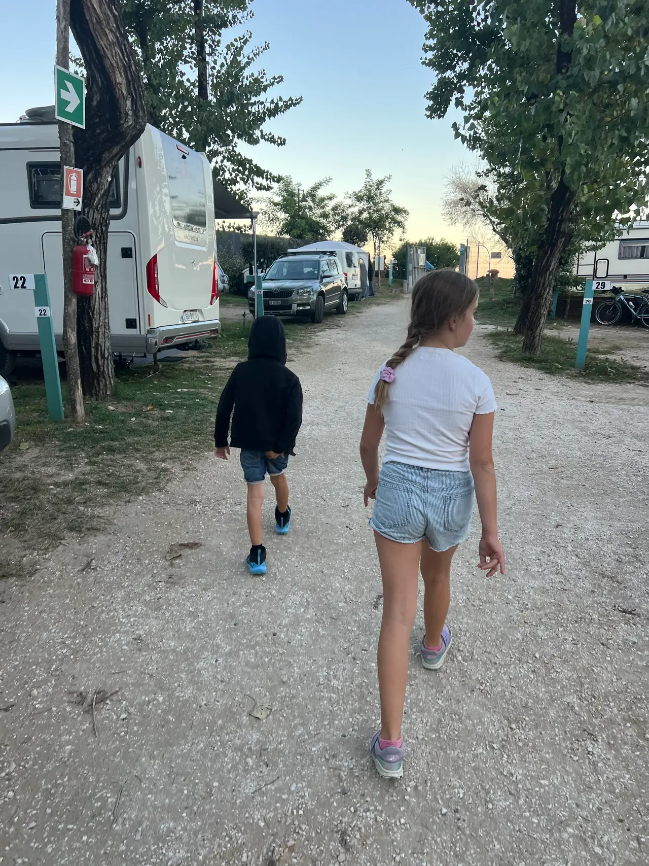 Děti jdou po prašné cestě mezi obytnými auty v kempu Santa Margherita v Caorle