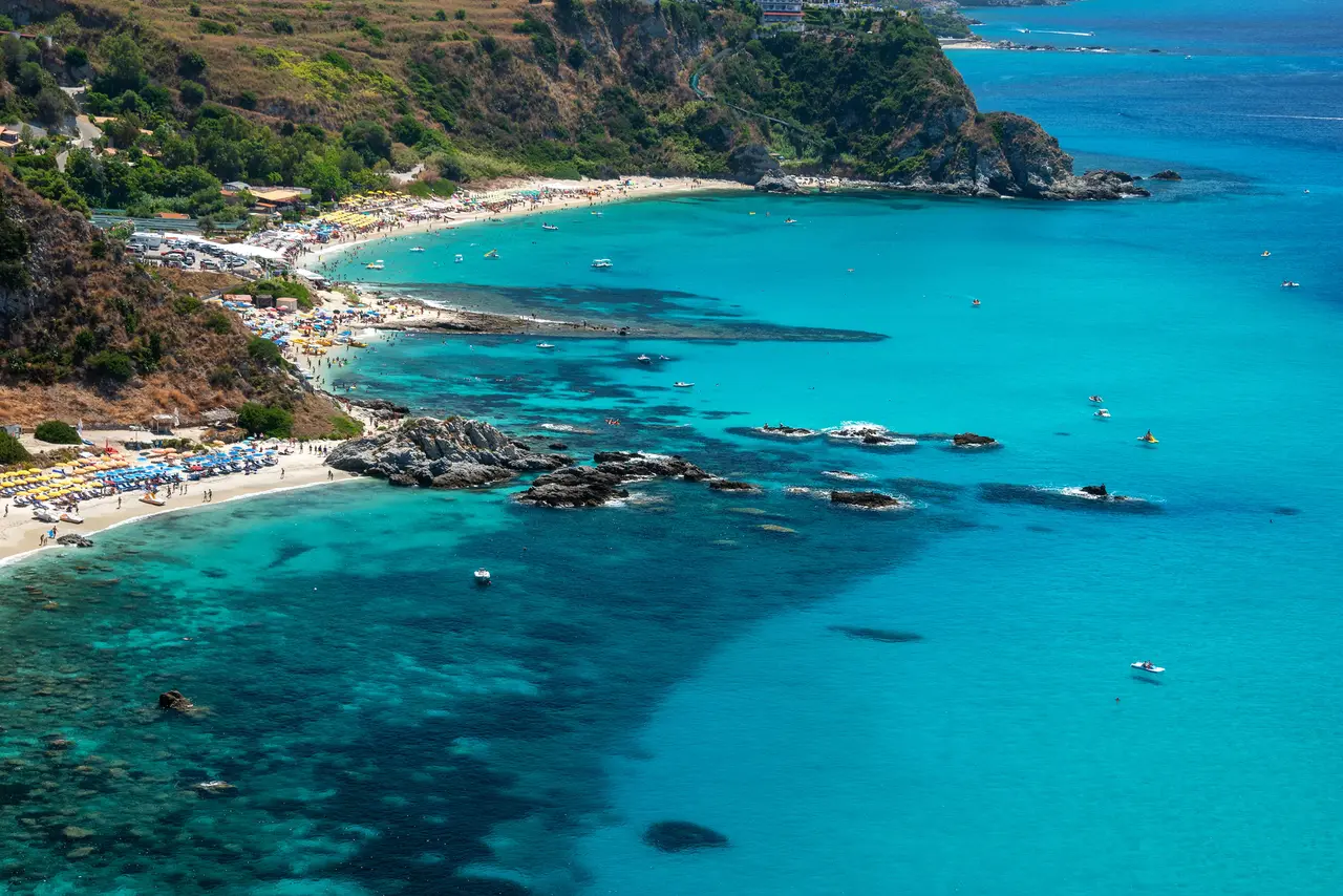 Zátoka Grotticelle na Capo Vaticano shora: tyrkysové moře, skaliska a pláže pod zeleným svahem