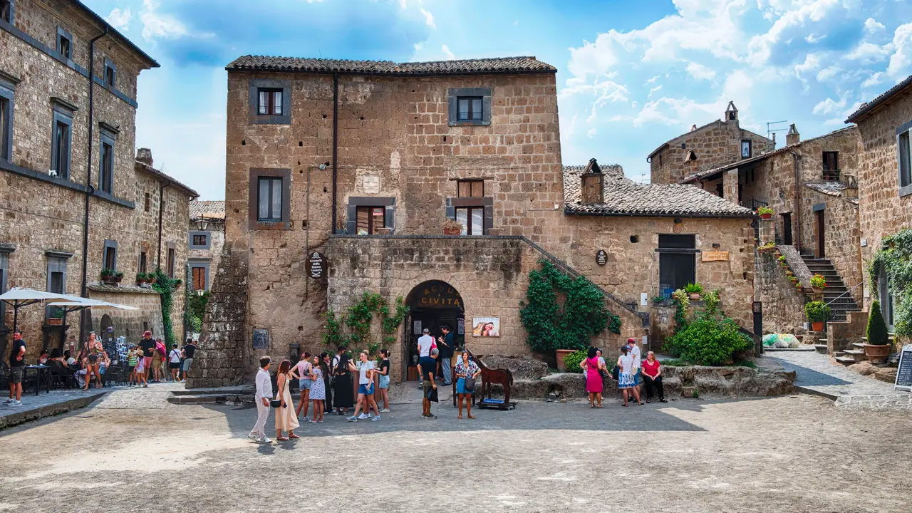 Hlavní náměstí v Civita di Bagnoregio s kamennými domy, turisty a typickou italskou atmosférou.