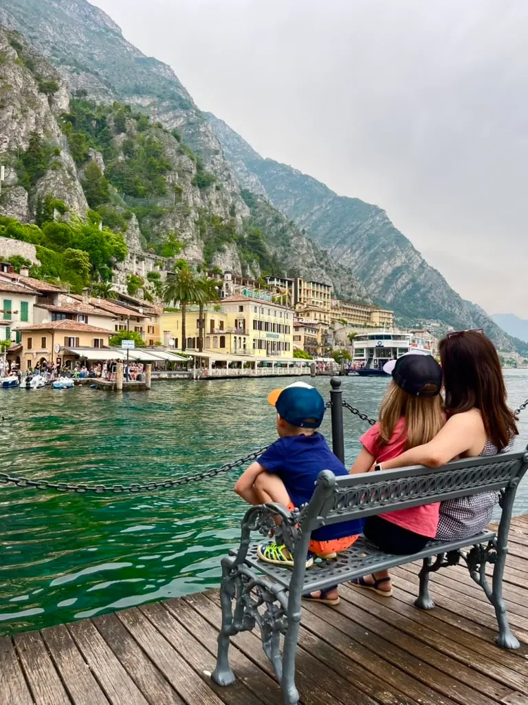 Monča, Niky a Filda sedí na lavičce v Limone sul Garda a pozorují malebné domy na pobřeží jezera Garda.