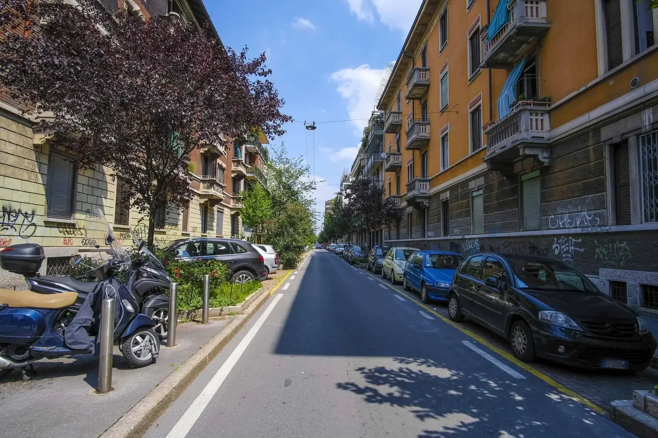 Úzká italská ulice s vyhrazenými žlutými parkovacími místy podél,
