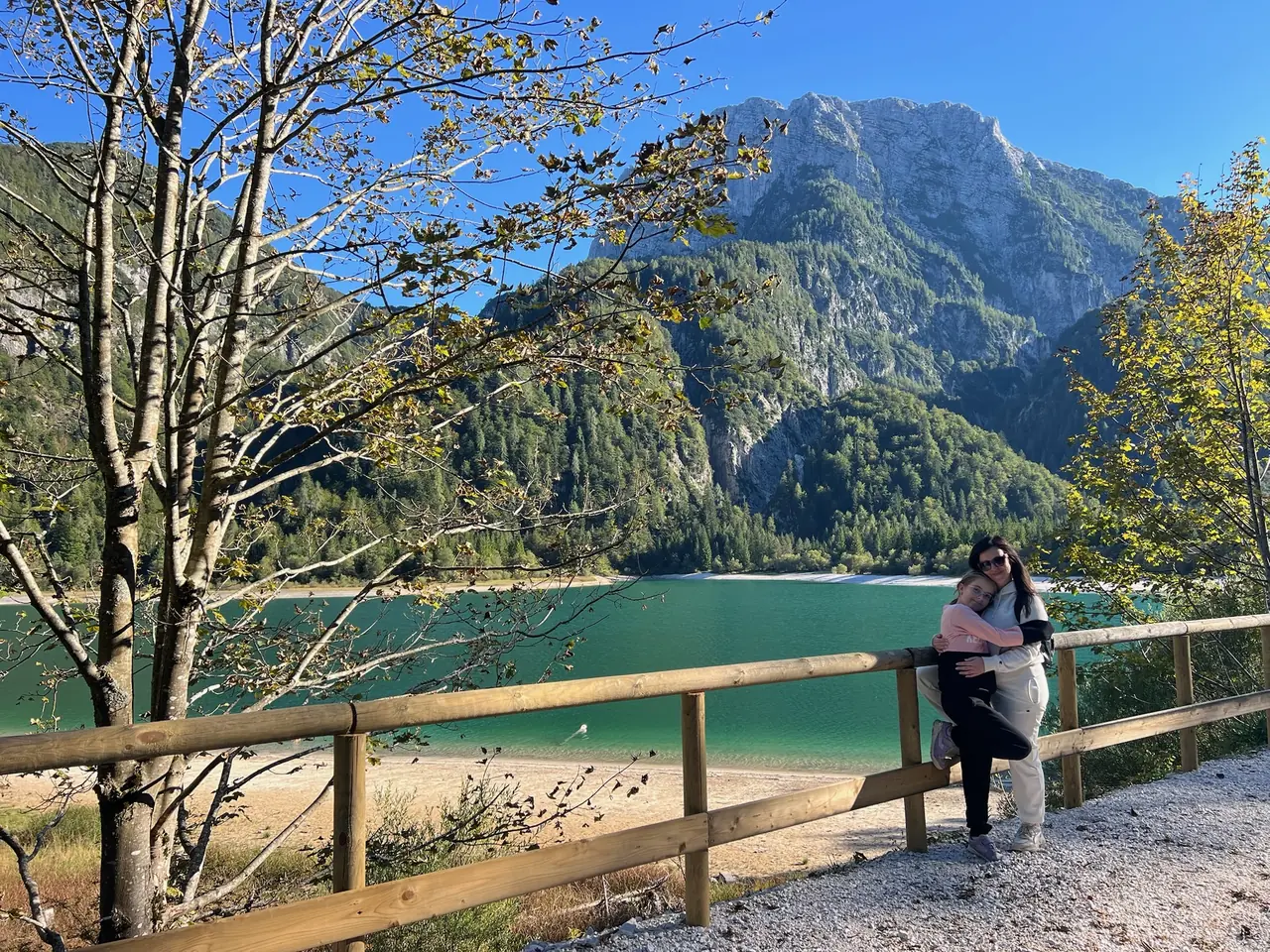 Monika s dcerou u dřevěného zábradlí nad Lago del Predil, za nimi jezero a hory