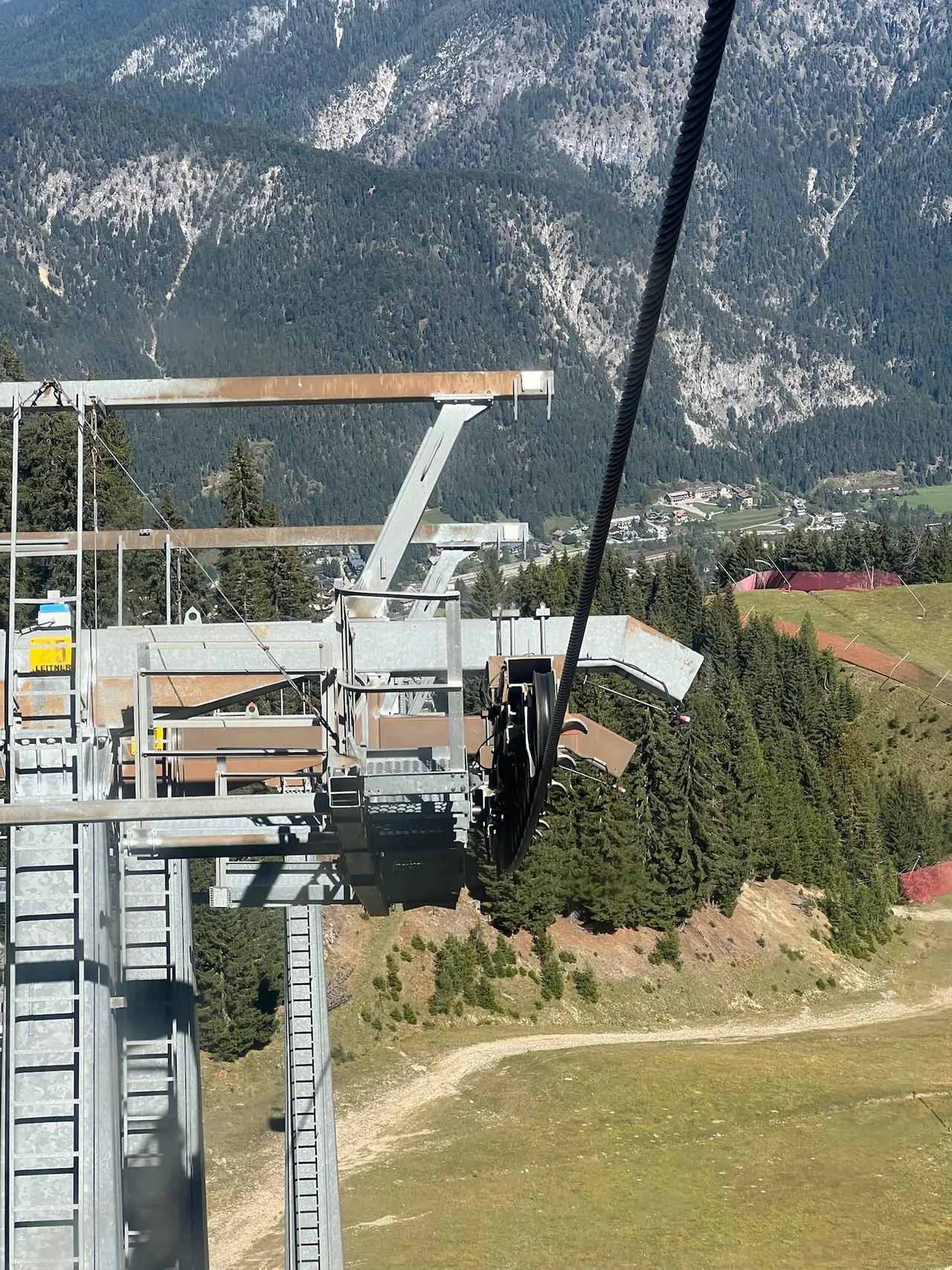 Kabinka lanovky nad lesem a sjezdovkou při jízdě dolů z Monte Lussari, v pozadí Julské Alpy