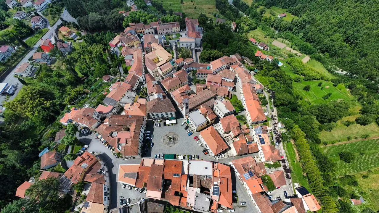 Letecký snímek historického centra Fivizzana s typickými červenými střechami domů seskupených kolem centrálního náměstí obklopeného zelenou toskánskou krajinou