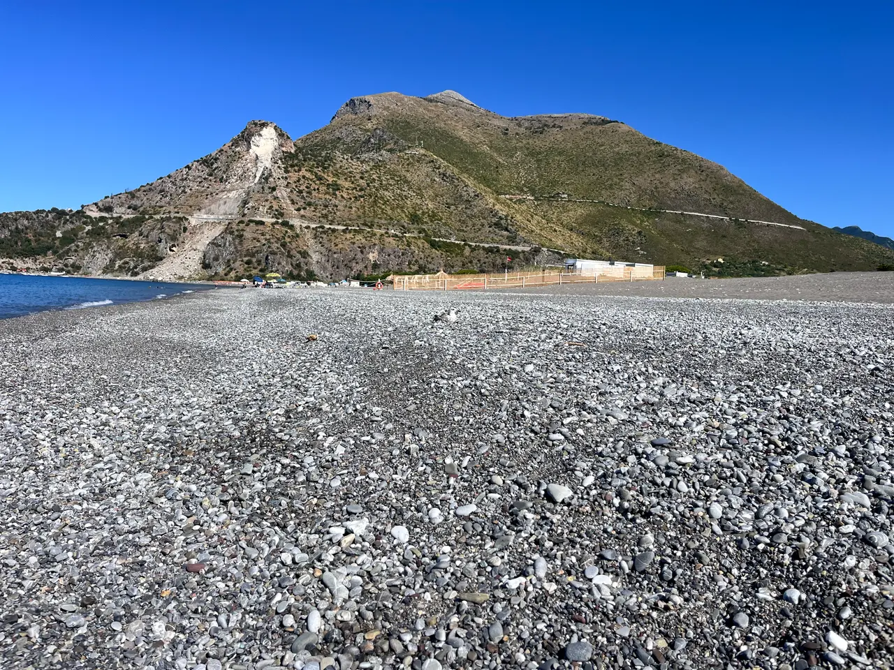 Hladké oblázky na pláži v Castrocuccu a kopec nad mořem