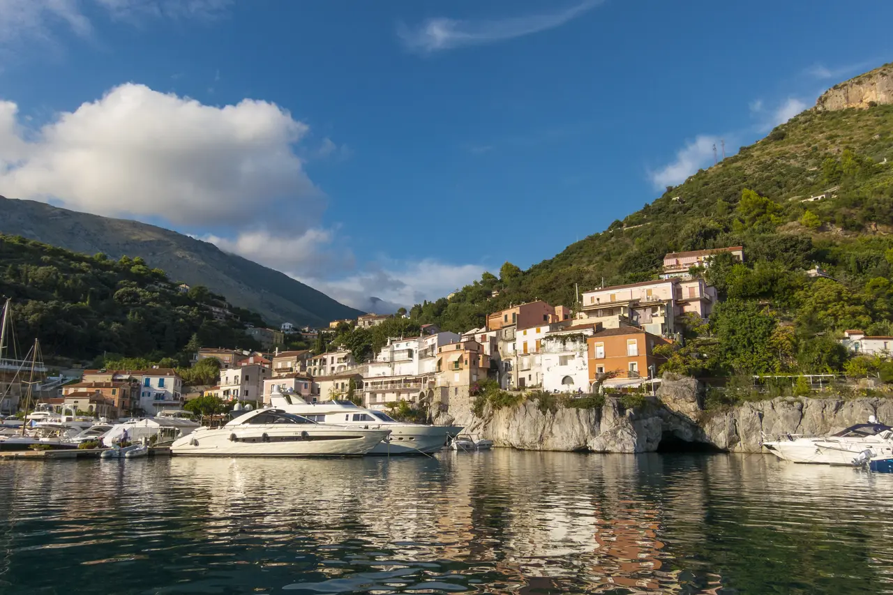 Přístav Porto di Maratea s loděmi a domy na zeleném svahu