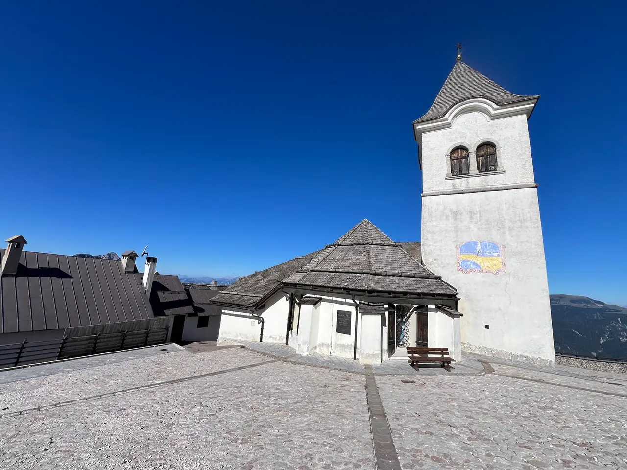 Bílá zvonice a kostel svatyně na Monte Lussari pod tmavě modrým nebem