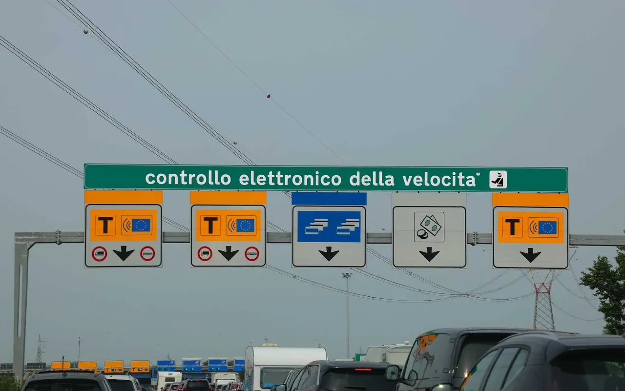 Nad dálnicí visí zelená tabule s nápisem kontrollo elettronico della velocita a barevnými značkami pro jednotlivé pruhy, kerá vám říkám který si vybrat.