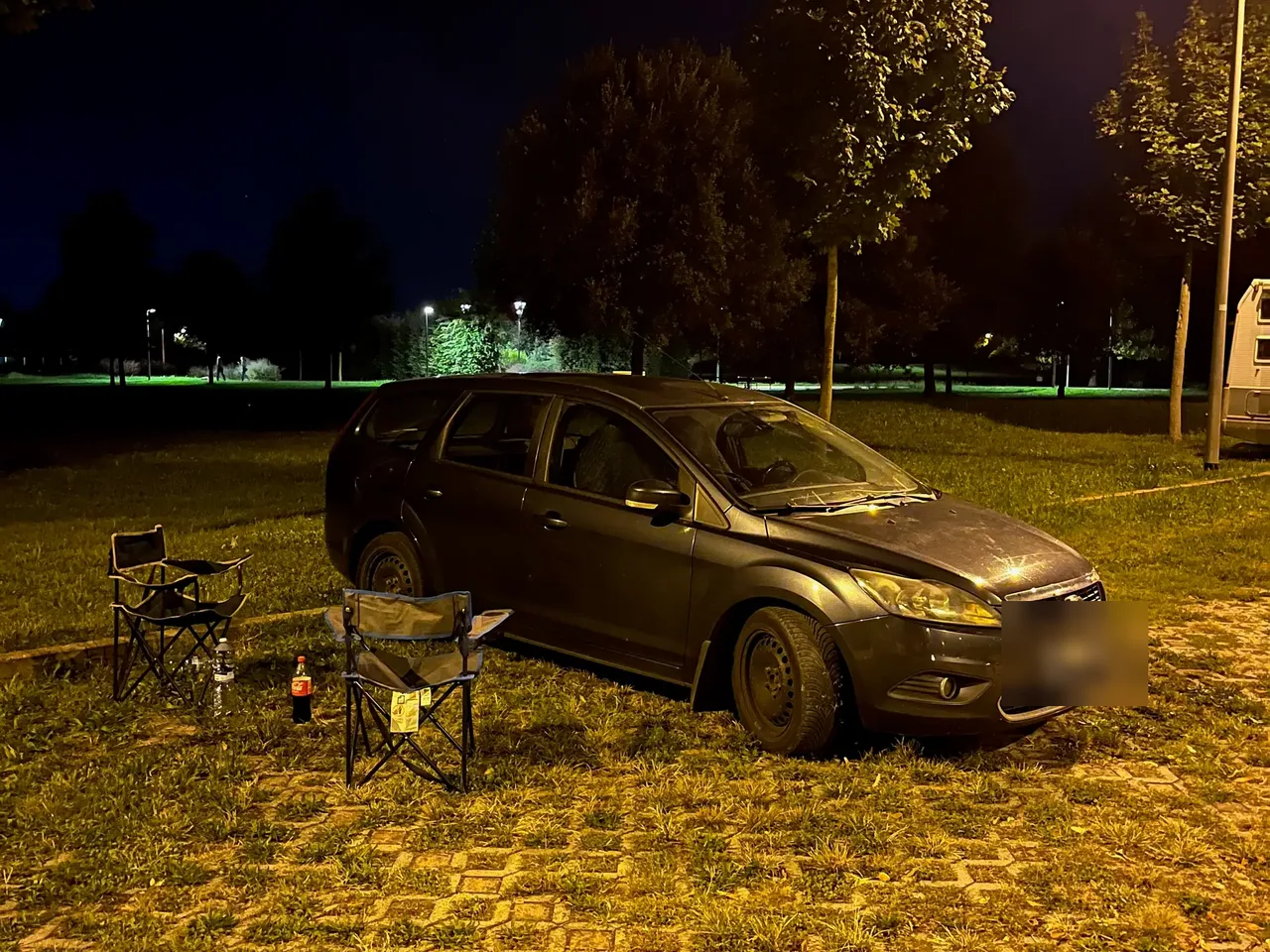 Naše auto a kempingové židličky v noci na louce v Lido di Jesolo