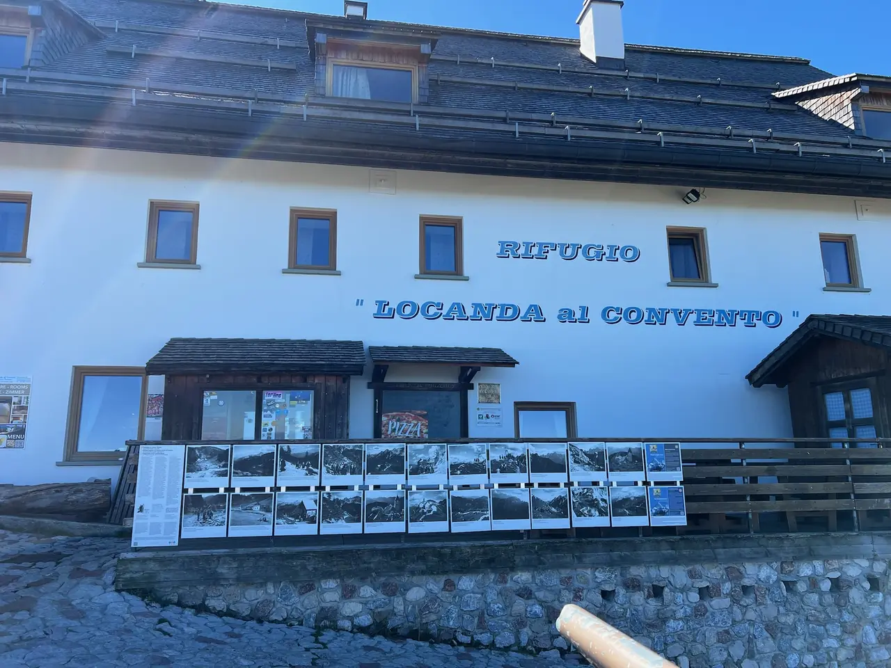 Bílá budova Rifugio Locanda al Convento na Monte Lussari s dřevěným balkonem