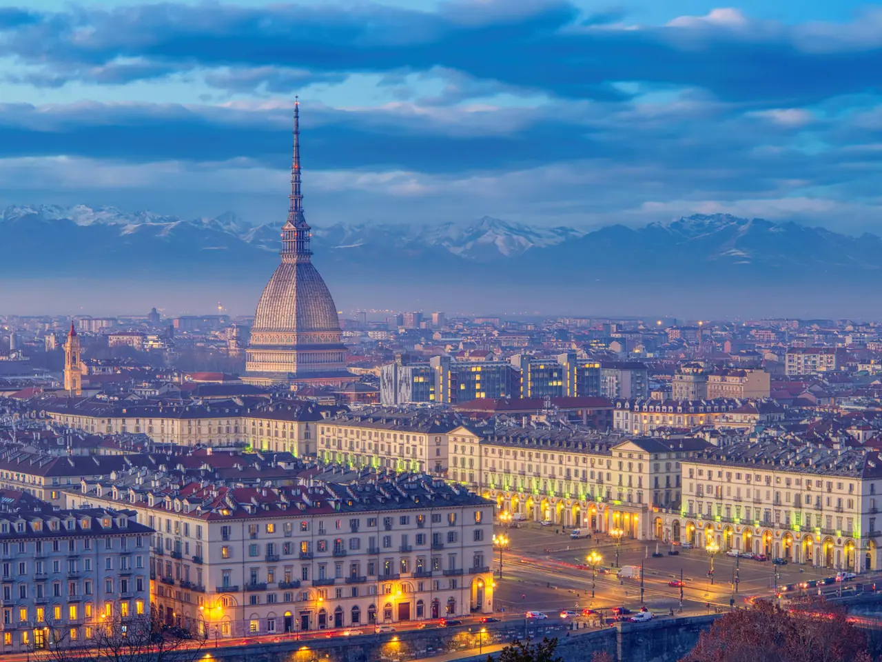Panoramic view of Turin's skyline at twilight featuring the iconic Mole Antonelliana and surrounding architecture.