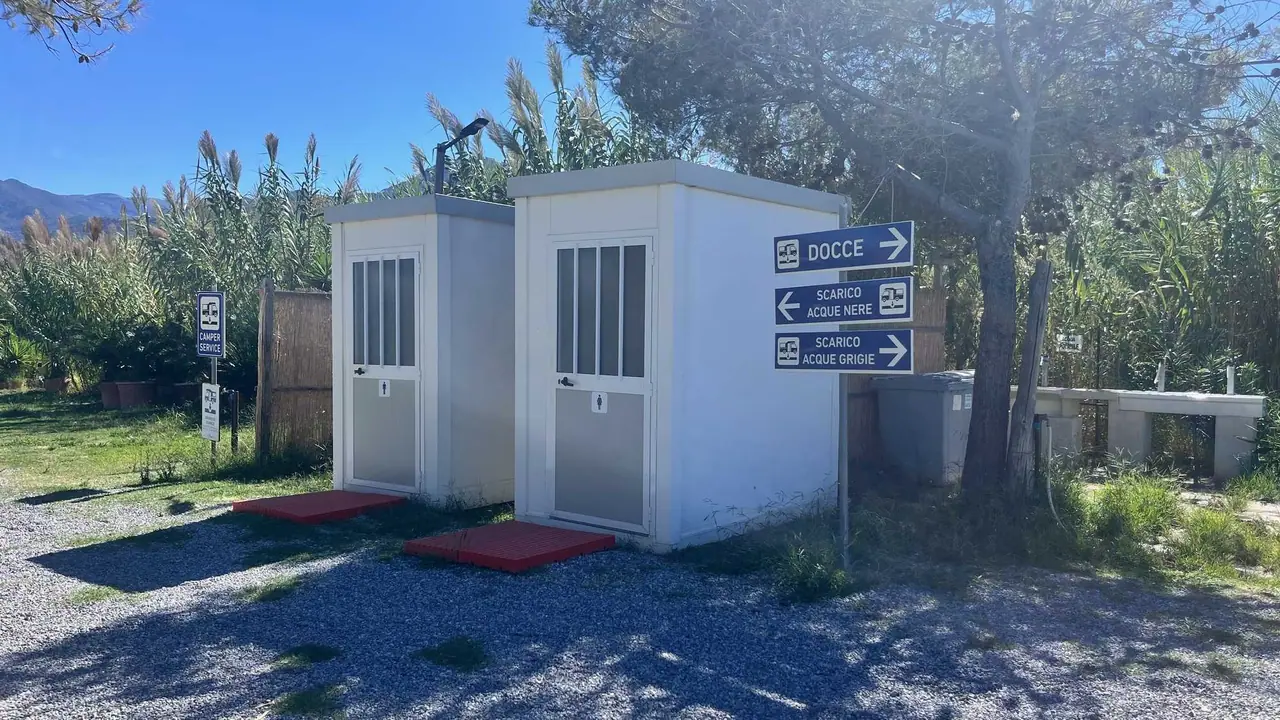 Bílé toalety v kempu u Maratey se směrovkami ke sprchám a výlevce