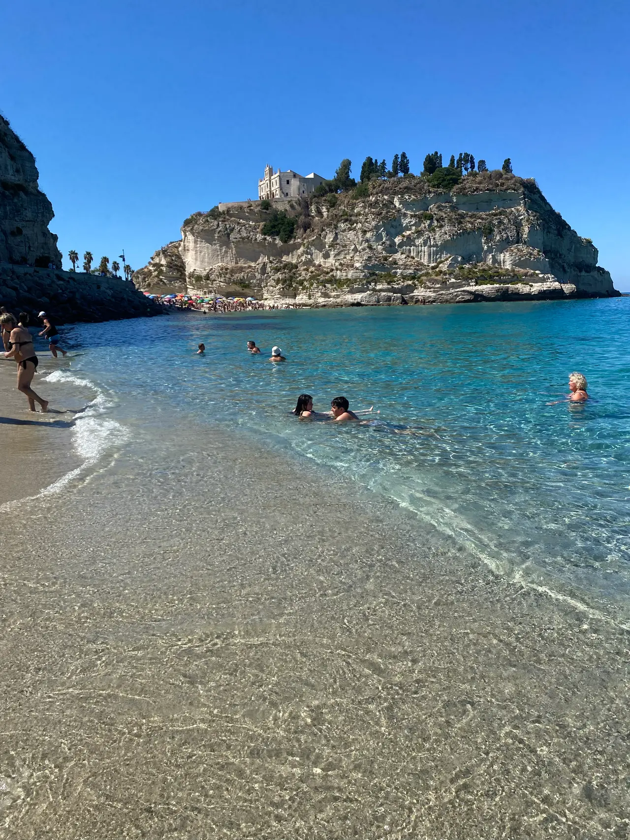 Pláž v Tropei s průzračnou vodou a skálou se svatyní Santa Maria dell'Isola