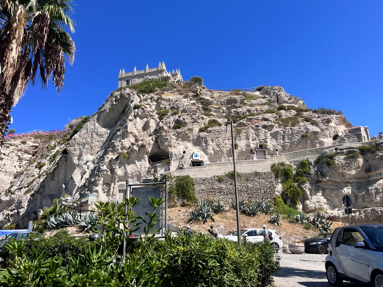 Skála se svatyní Santa Maria dell'Isola v Tropei od parkoviště u pláže