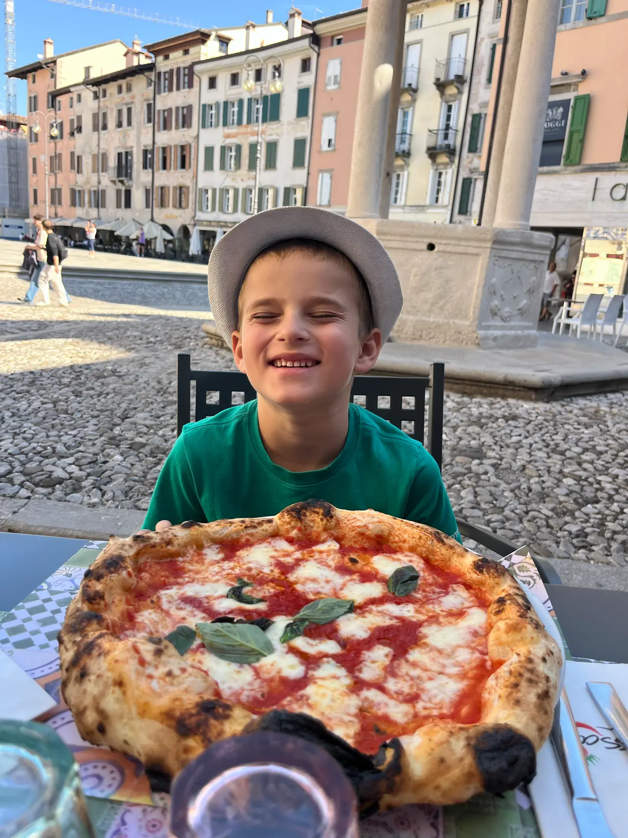 Syn s pizzou Margheritou na zahrádce restaurace na Piazza Matteotti v Udine