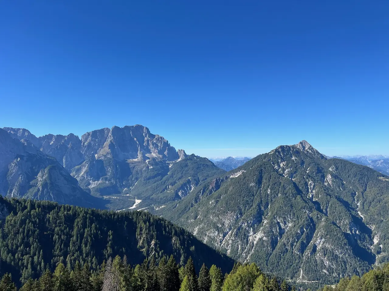 Výhled z Monte Lussari na skalnaté štíty a zalesněná údolí Julských Alp