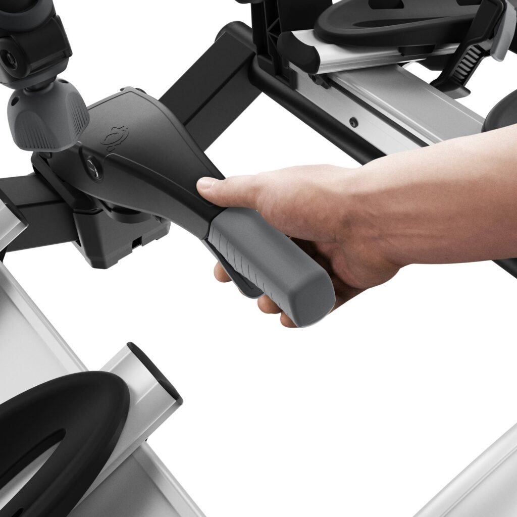 Ruka drží ergonomickou rukojeť nosičče kol Thule VeloCompact při montáži na tažné zařízení automobilu